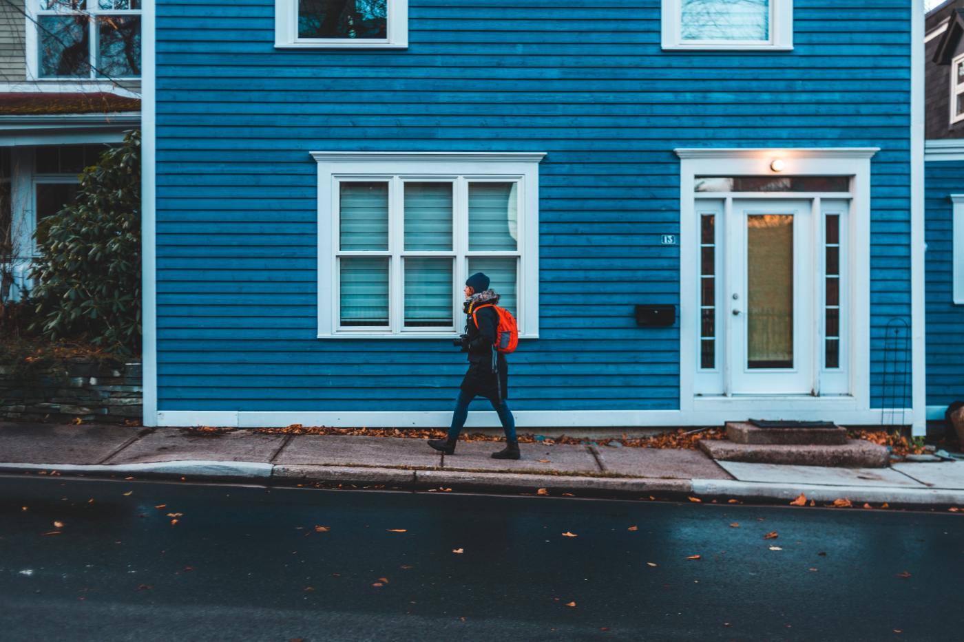 person walking in front of a big, blue house